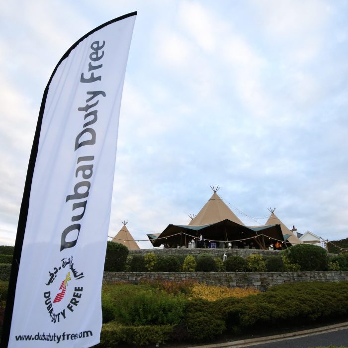 Tipi setup for Dubai Duty Free, corporate flag blows in the foreground with a three Tipi set up in the background