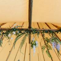Fabulous green foliage, lilac and white florals hang from the crossbeams inside a Tipi