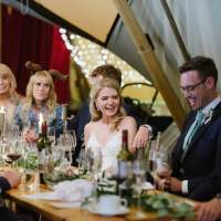 The bride and guests laugh and chat as they enjoy their meal