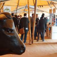 A decorative Bull sits inside a tipi, festival goers walk around enjoying the Odaios Food Fair