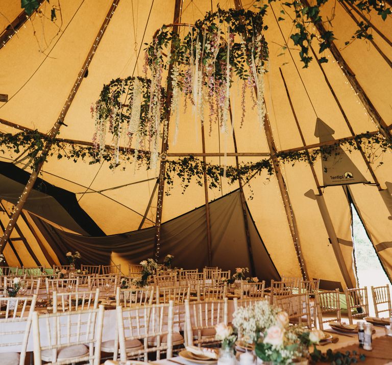 Inside Tipi decorated with natural foliage and hanging floral hoops