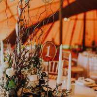 Rustic willow and flower centrepieces sit with a wooden table number
