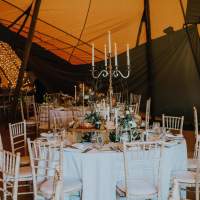 Round tables sit inside a tipi, decorated with silver candelabra and rustic flower centrepieces