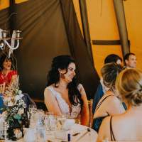 The bride sits smiling at a round table that has a silver candelabra centrepiece