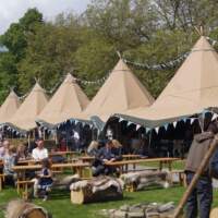 Festival Tipis are in a line with guests sitting at Magnakata picnic tables in front enjoying the Food Festival