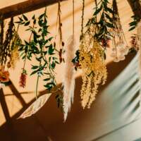 Lovely dried flowers and feathers hang from the tipi crossbeams, tied with string.
