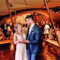 The bride & Groom have their first dance inside the tipis, guests surround them