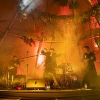 A band is lit up with warm yellow uplighters on a Magnakata stage at Tipi Party