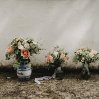 Three bouquets of flowers stand in ceramic and glass vases