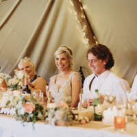 The bride and groom sit at a table with their wedding party