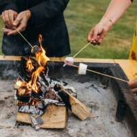 Close up of wedding guests toasting marshmallows on magnakatas open firepit