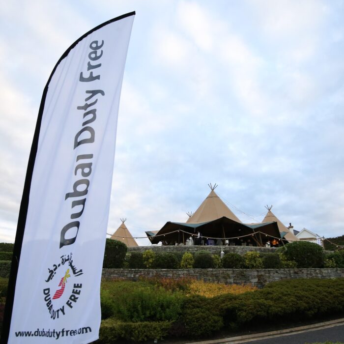 Tipi setup for Dubai Duty Free, corporate flag blows in the foreground with a three Tipi set up in the background