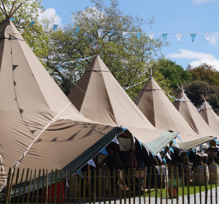 Six Tipi's line up at a food festival with colourful blue bunting decoration