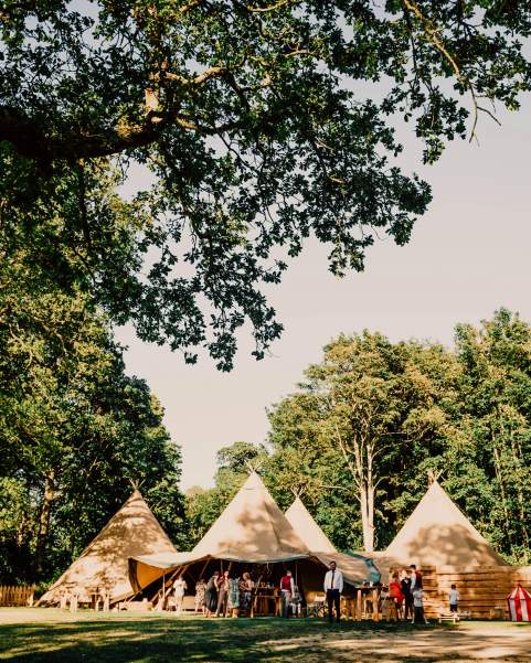 Four tipis sit amongst the trees at Finnebrogue Woods on a beautiful summers' evening