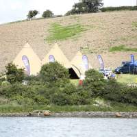 Three Tipis stand beside gazebos and Flags at Skiffie Festival set in Delamont Country Park