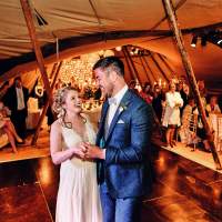 The bride & Groom have their first dance inside the tipis, guests surround them