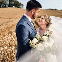 The bride and groom look at eachother in a wheat field