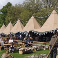 Festival Tipis are in a line with guests sitting at Magnakata picnic tables in front enjoying the Food Festival
