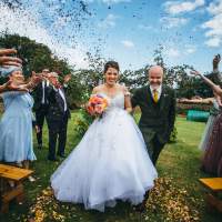 Bride and Groom walk through their wedding guests with gold confetti being thrown around them
