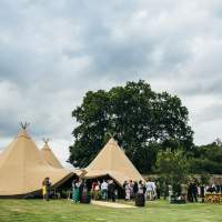 Wedding guests crowd around the opening of a three tipi wedding tent