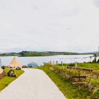 Two tipis sit on the donegal coast, with bunting decorating a path that leads to the tipis