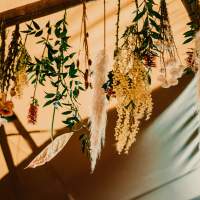 Lovely dried flowers and feathers hang from the tipi crossbeams, tied with string.