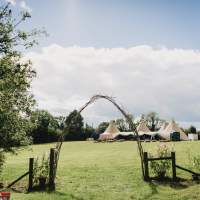 A rustic wooden arch stands as an entrance to the Tipi wedding reception