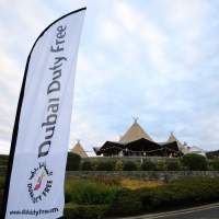 Tipi setup for Dubai Duty Free, corporate flag blows in the foreground with a three Tipi set up in the background