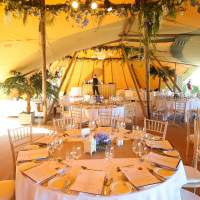 Inside the Dubai Duty Free Tipi corporate event is decorated with palm trees and formal dining, a wooden bar sits in the back