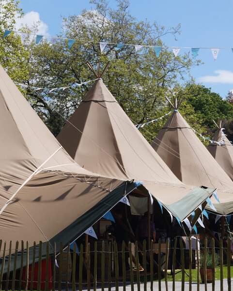 Six Tipi's line up at a food festival with colourful blue bunting decoration