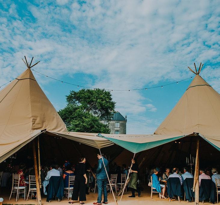 Open sided entrance to a five tipi wedding reception, inside is crowded with guests sitting at tables
