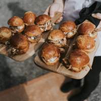 Delicious burgers are carried on wooden trays by a waitress