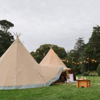 Lovely two Tipi Wedding reception stands in Mount Stewart with festoon lighting and a firepit in front of the entrance
