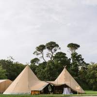 A magnificent two Tipi Wedding reception sits on the grounds of Mount Stewart with lush green trees covering the background